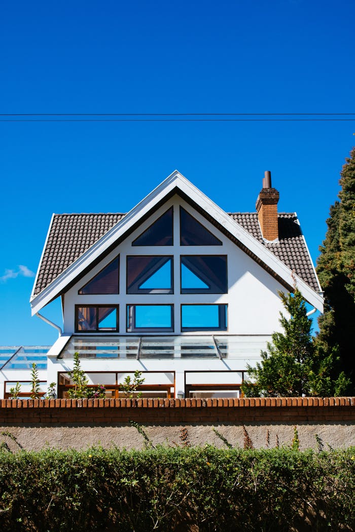 creative-03 A modern A-frame house with large windows against a clear blue sky, showcasing contemporary architecture.
