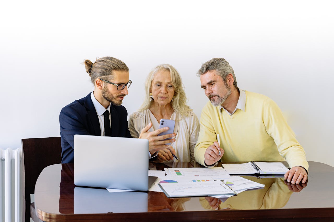 mobile-01 Three individuals collaborating on financial documents during a business meeting.
