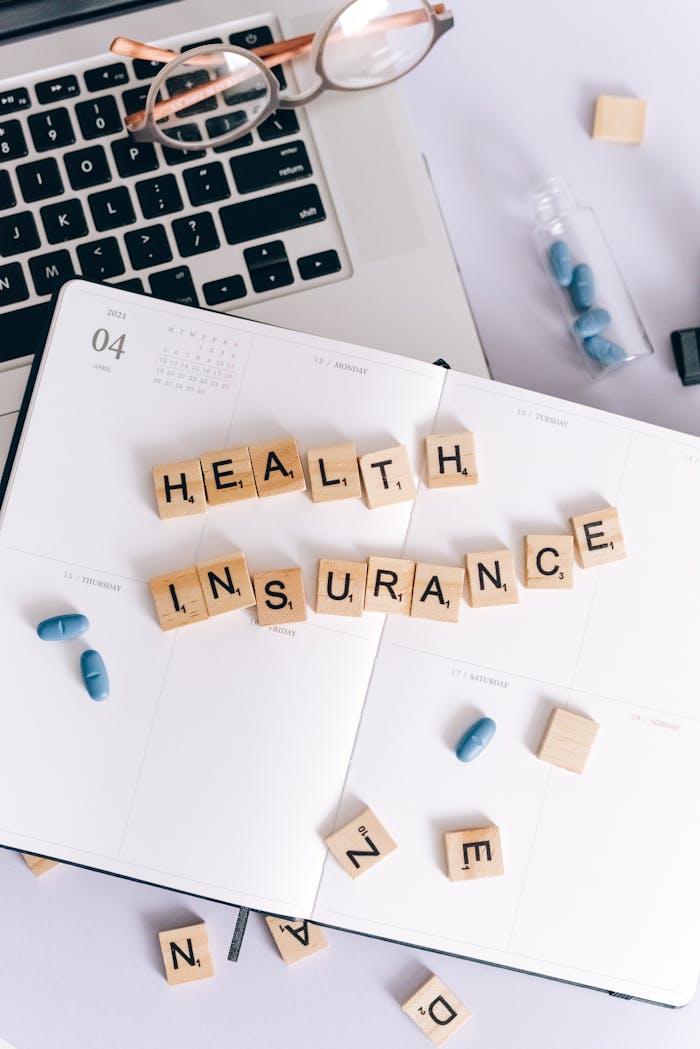 creative-03 Top view of health insurance planning with scrabble tiles, glasses, and pills.